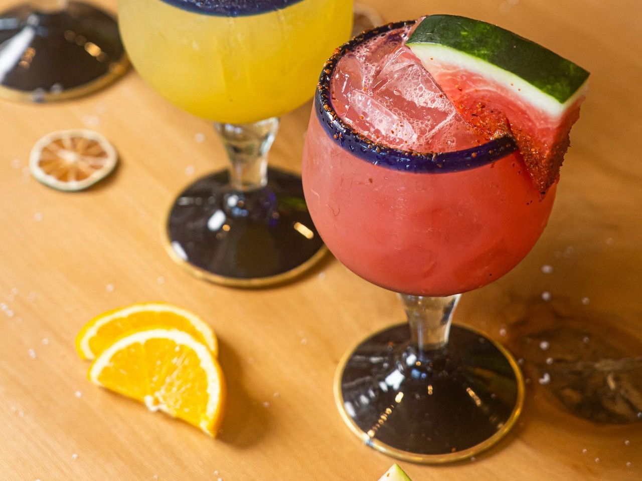 a glass of red liquid with fruit and a slice of lemon